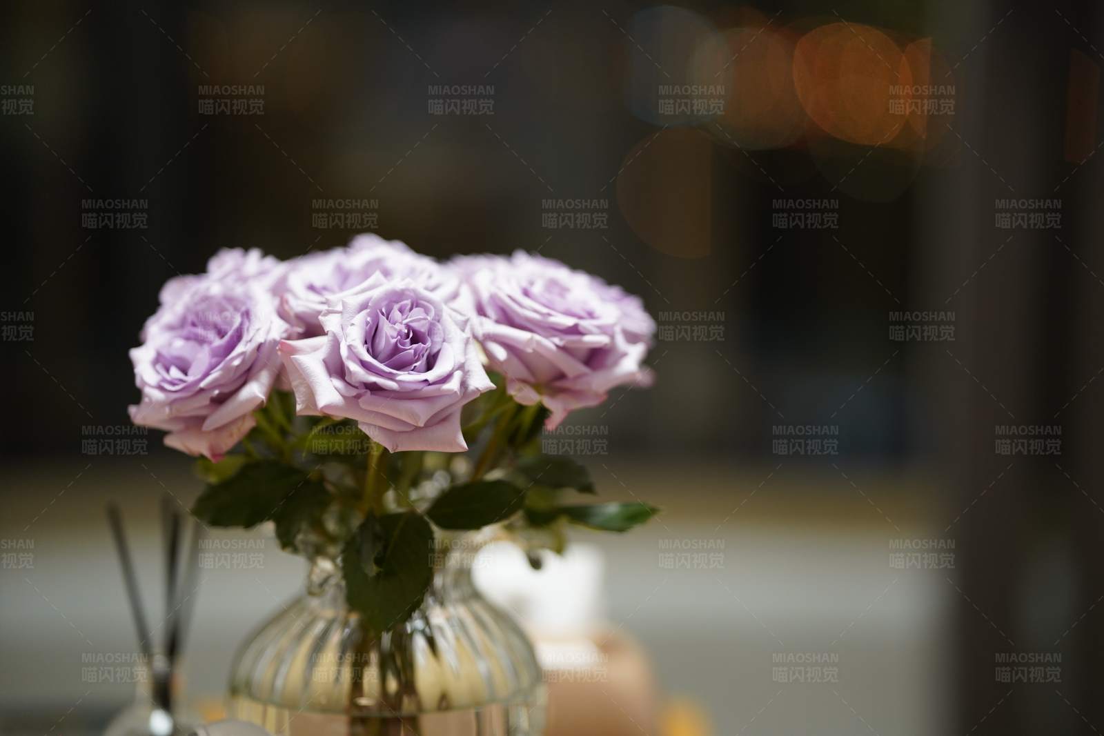 紫色玫瑰花束插在透明花瓶中图片