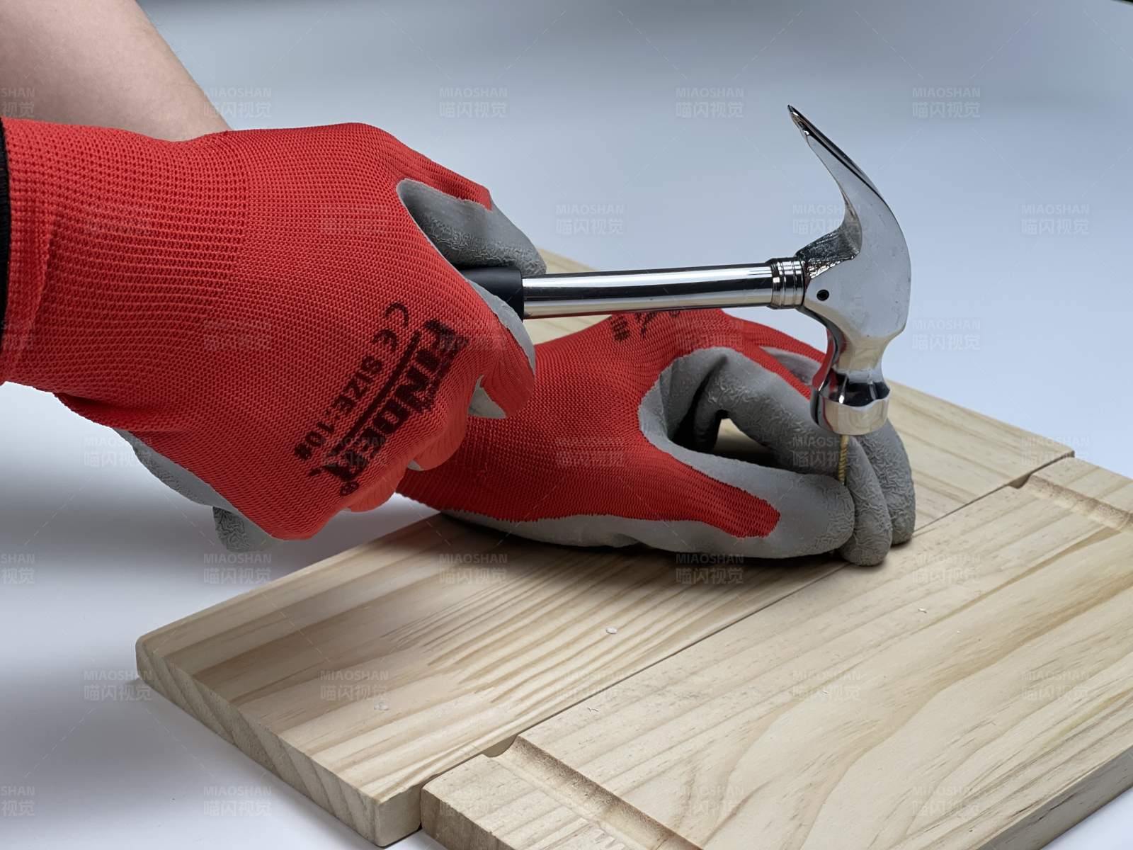 戴手套的人用锤子敲钉子图片
