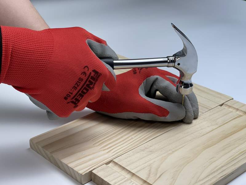 戴手套的人用锤子敲钉子图片