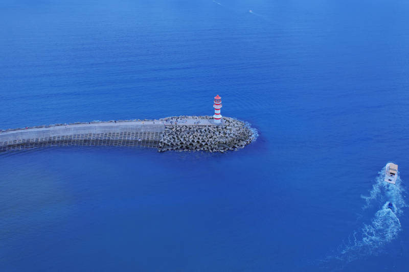 蓝色海洋中的灯塔与船只图片