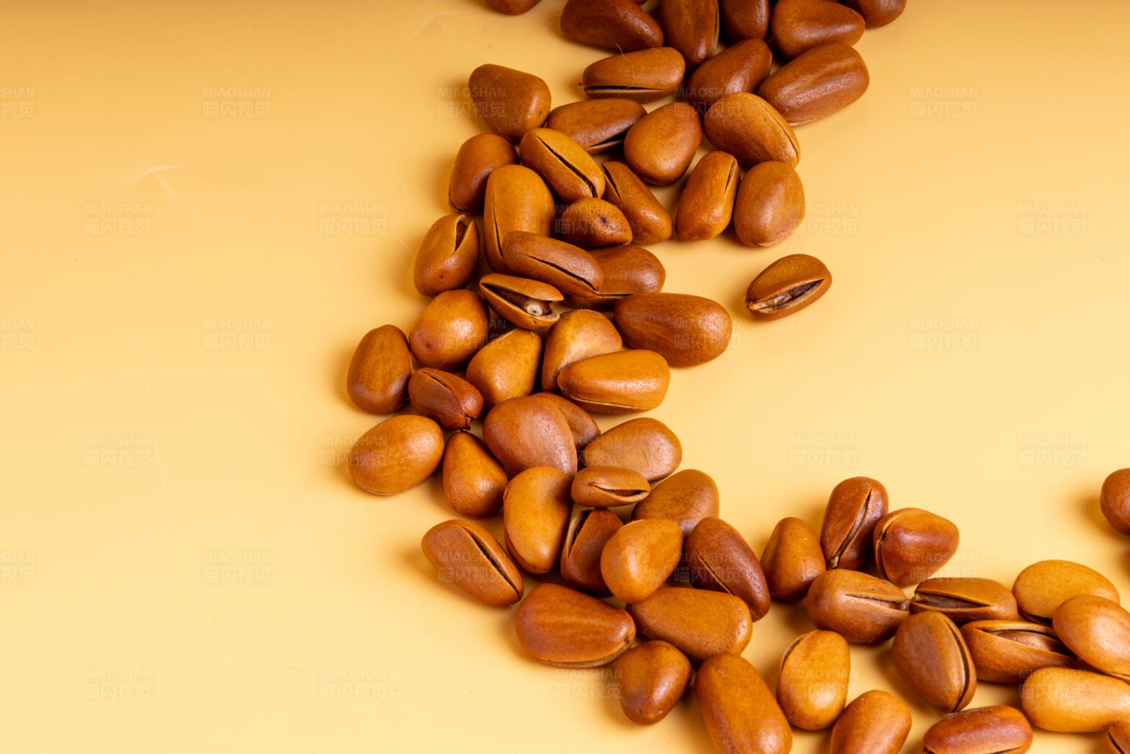 松子散落在黄色背景上图片