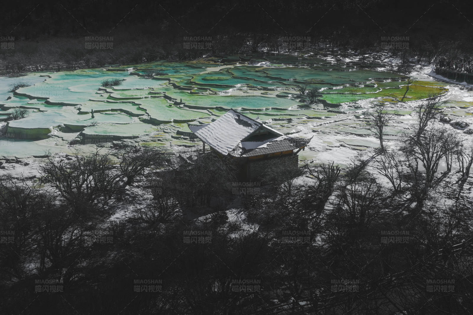 雪中孤屋与彩色湖泊图片