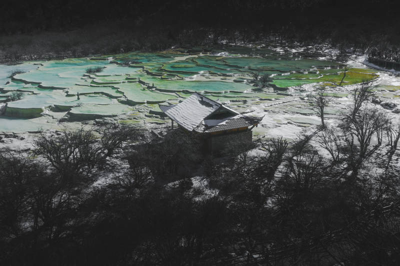 雪中孤屋与彩色湖泊图片