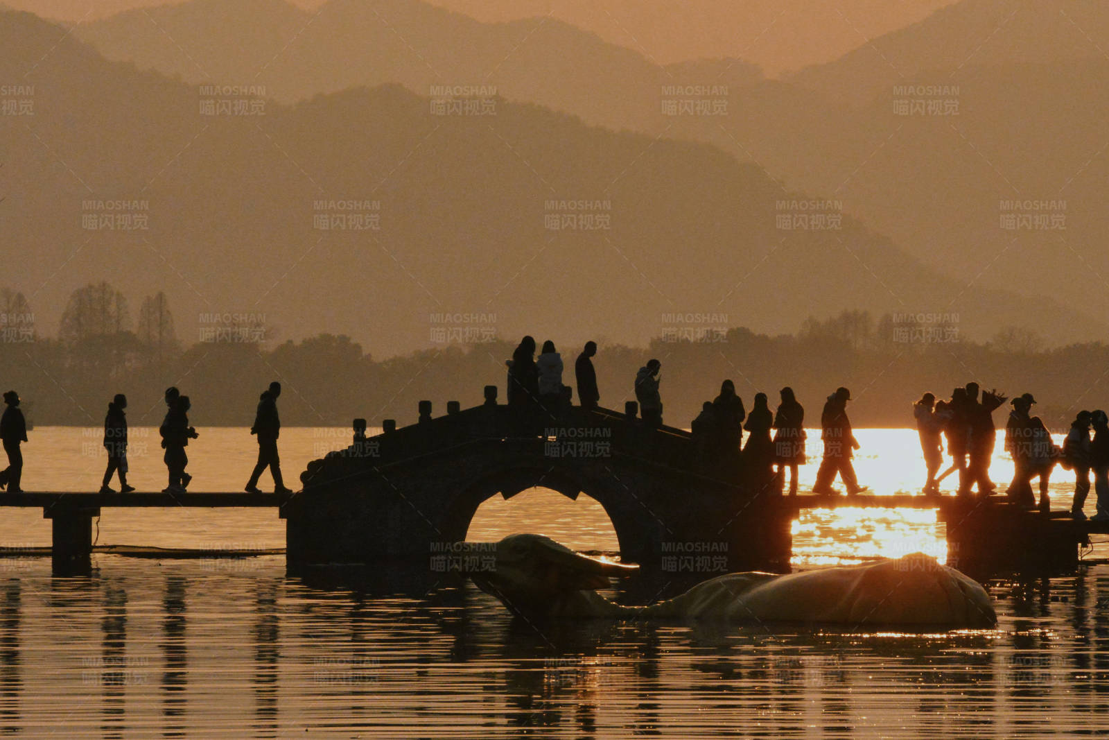 西湖夕阳下的桥上行人图片