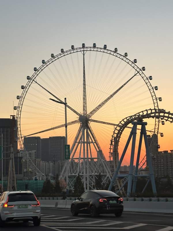 锦江乐园夕阳下的摩天轮与车流图片