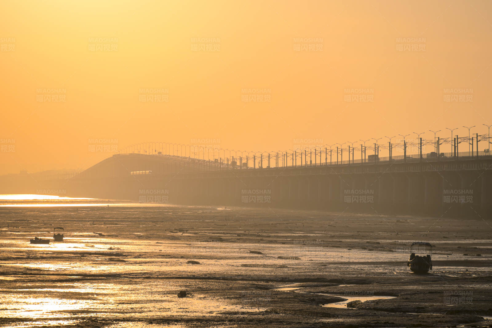 夕阳下的海桥与渔船图片