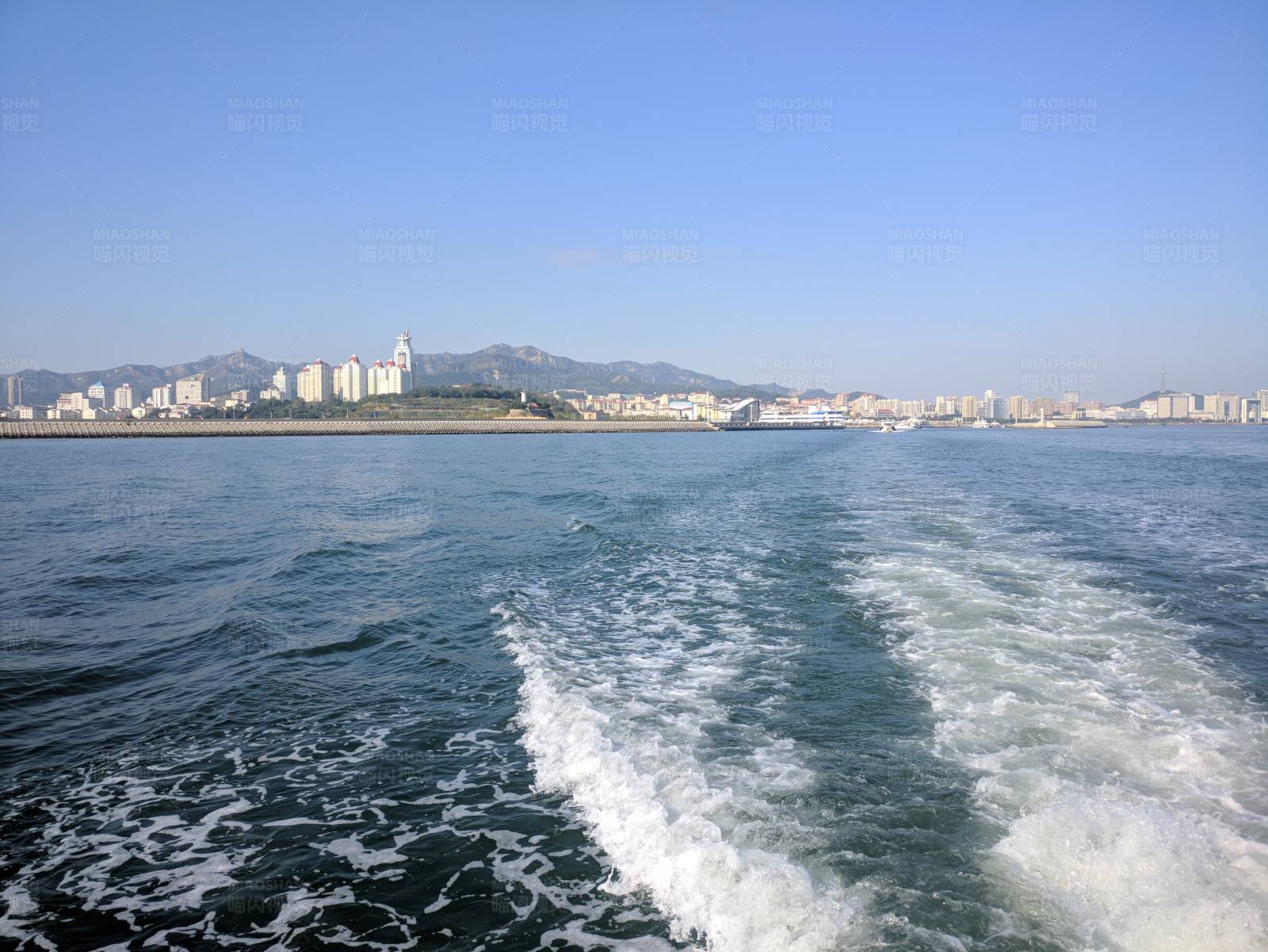 船后海浪与城市天际线图片