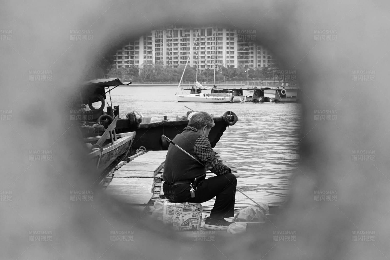 透过圆孔中老人钓鱼的背影图片