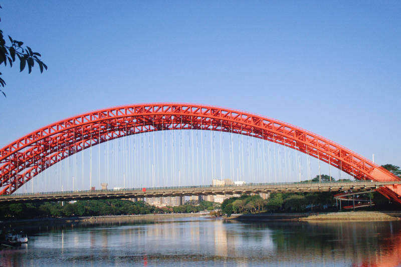 红色拱桥横跨河面图片