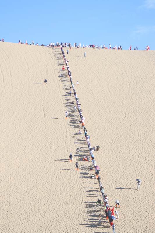 攀登沙丘的人群图片