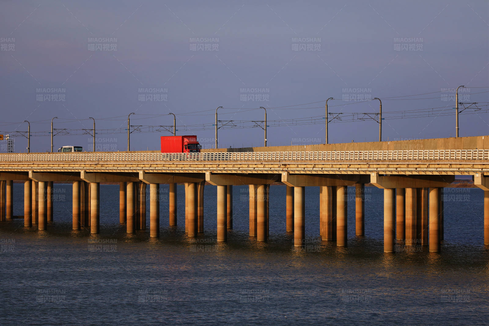 南京石臼湖红色货车驶过夕阳下的大桥图片