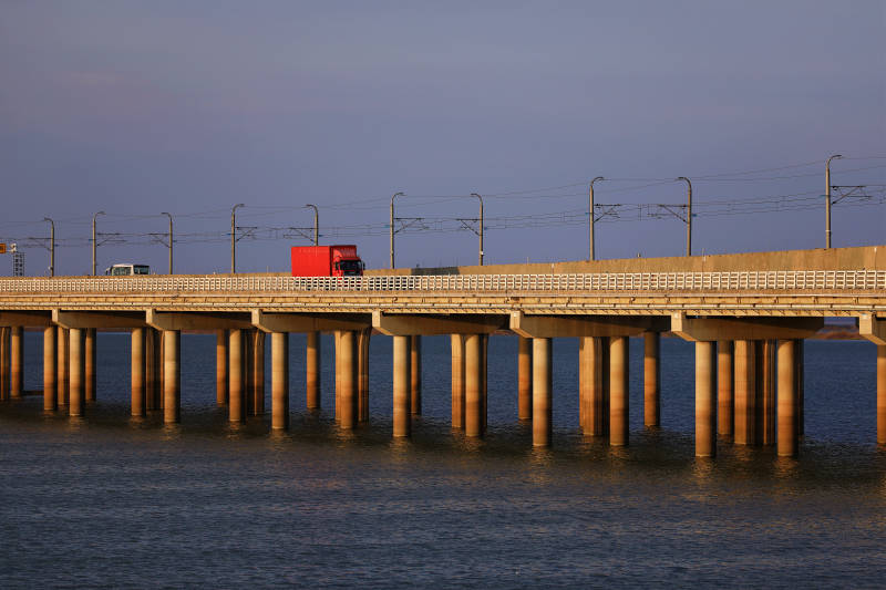 南京石臼湖红色货车驶过夕阳下的大桥图片