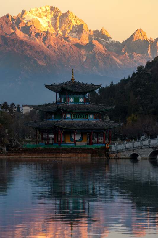 玉龙雪山晨曲：日照金山映照下的湖亭倒影图片