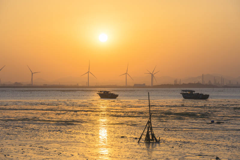 夕阳下的海上风车与渔船图片