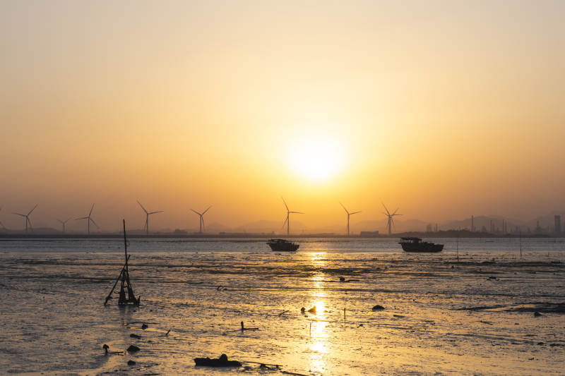 夕阳下的风车与渔船图片