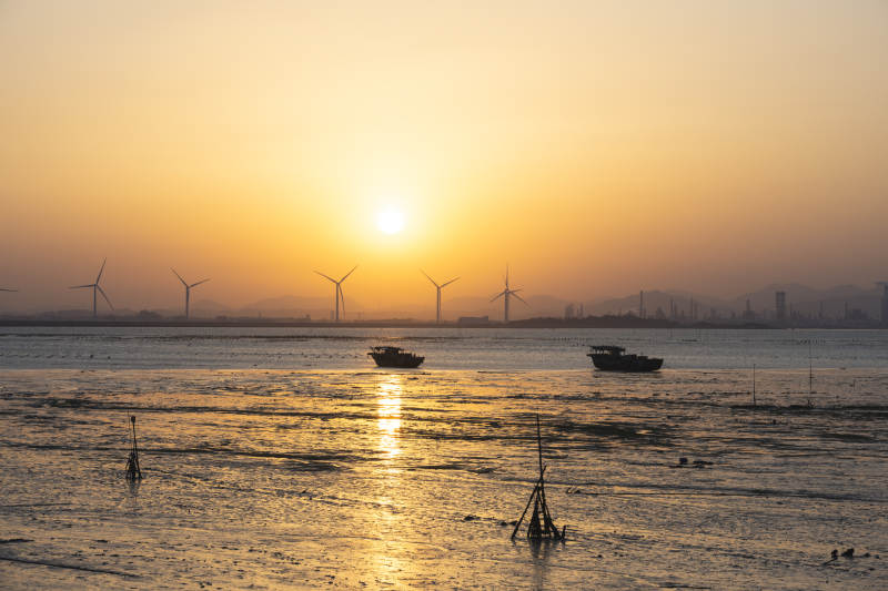 夕阳下的海上风车与渔船图片