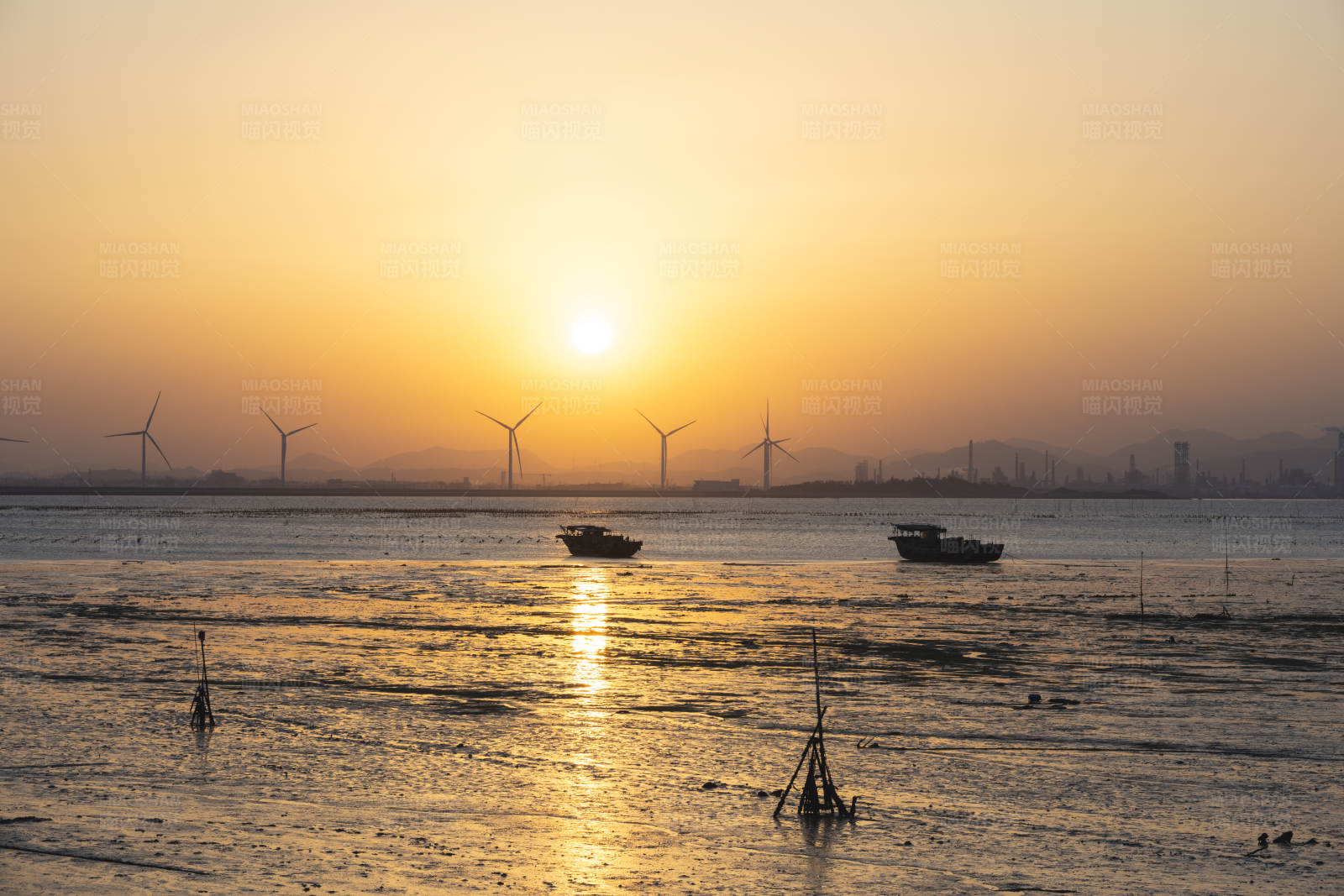 夕阳下的海上风车与渔船图片