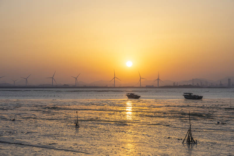 夕阳下的风车与渔船图片