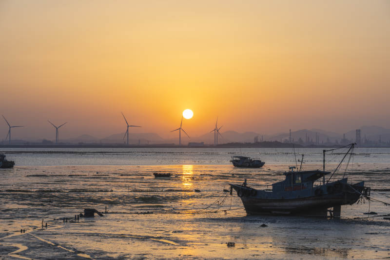 夕阳下的风车与渔船图片