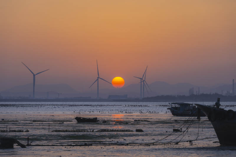 夕阳下的风车与渔船图片