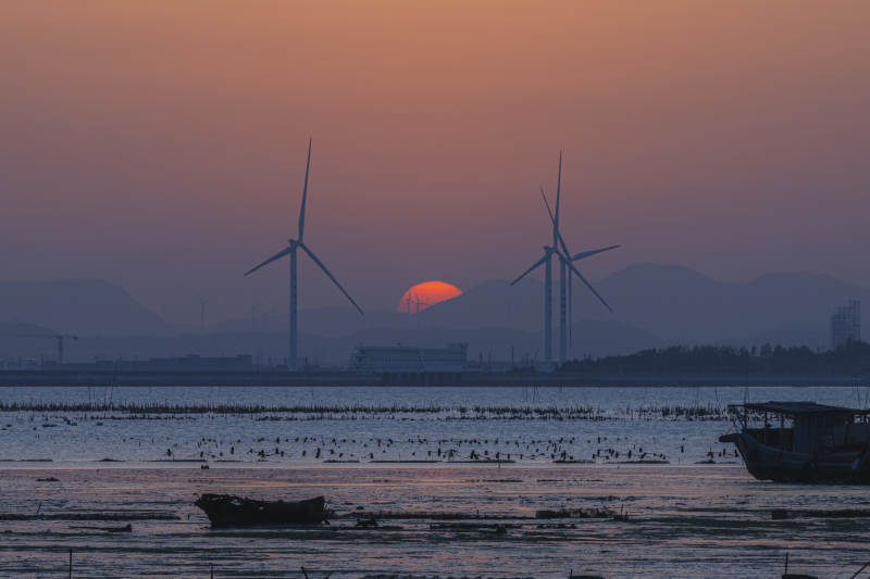 夕阳下的风车与渔船图片