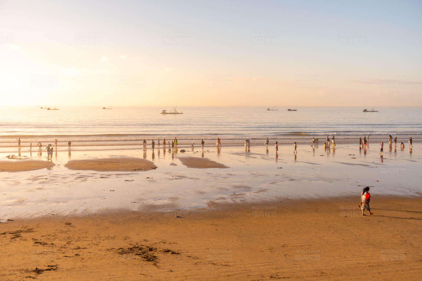 夕阳下的海滩人群图片