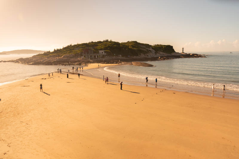 东山岛夕阳下的海滩与人群图片
