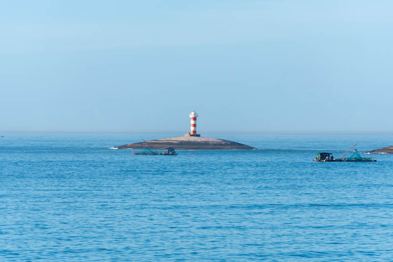 海上灯塔与渔船图片