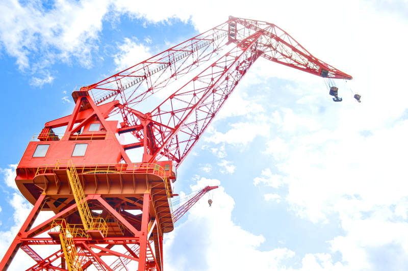 红色起重机在蓝天白云下图片