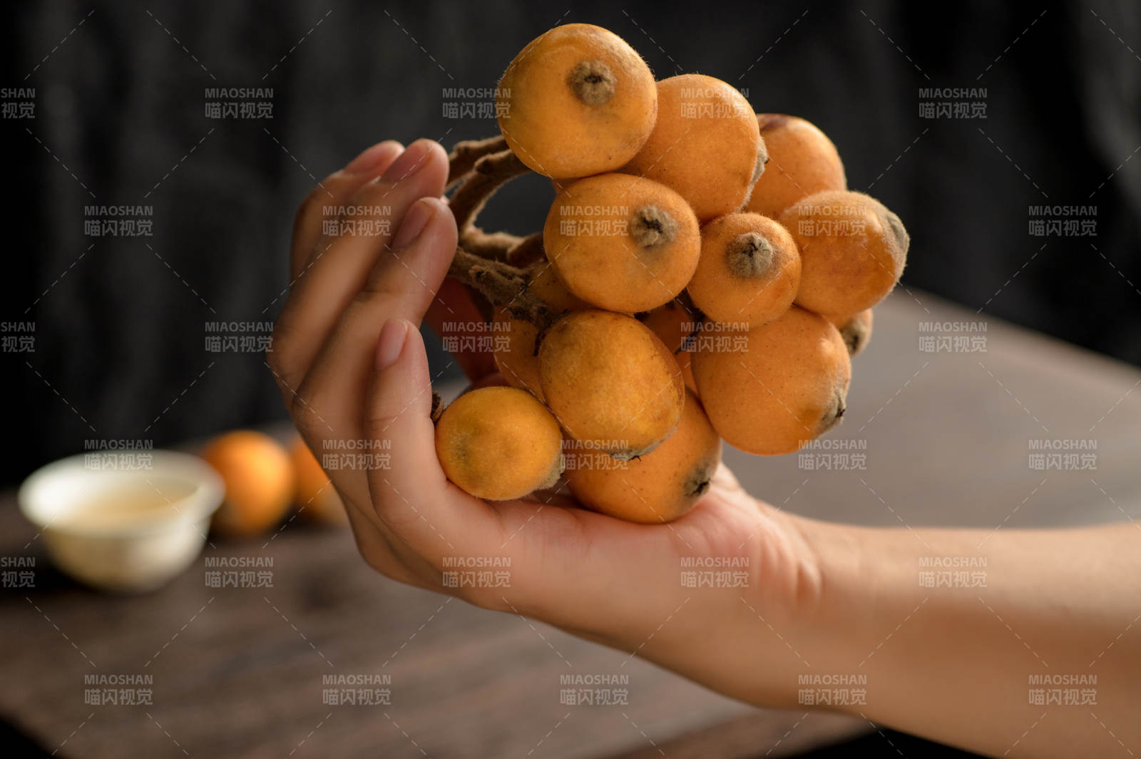 手持一串橙色枇杷图片