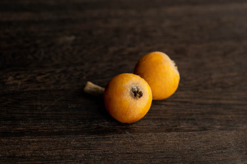 木桌上两个橙色枇杷图片