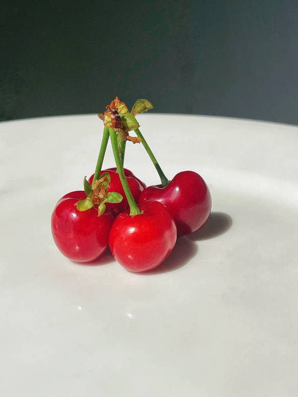 白色盘中四颗红樱桃开花图片