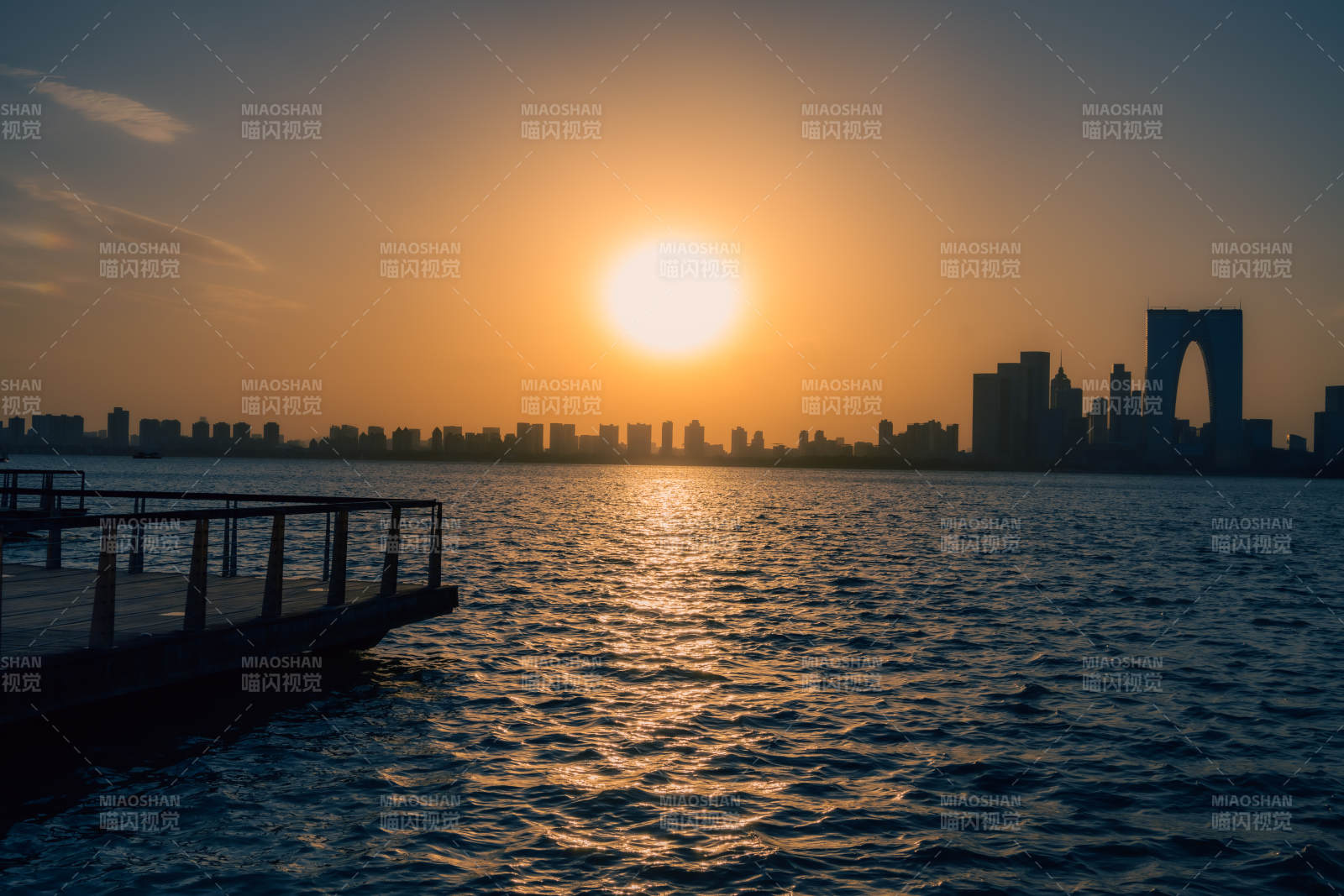 湖畔夕阳映城市剪影图片