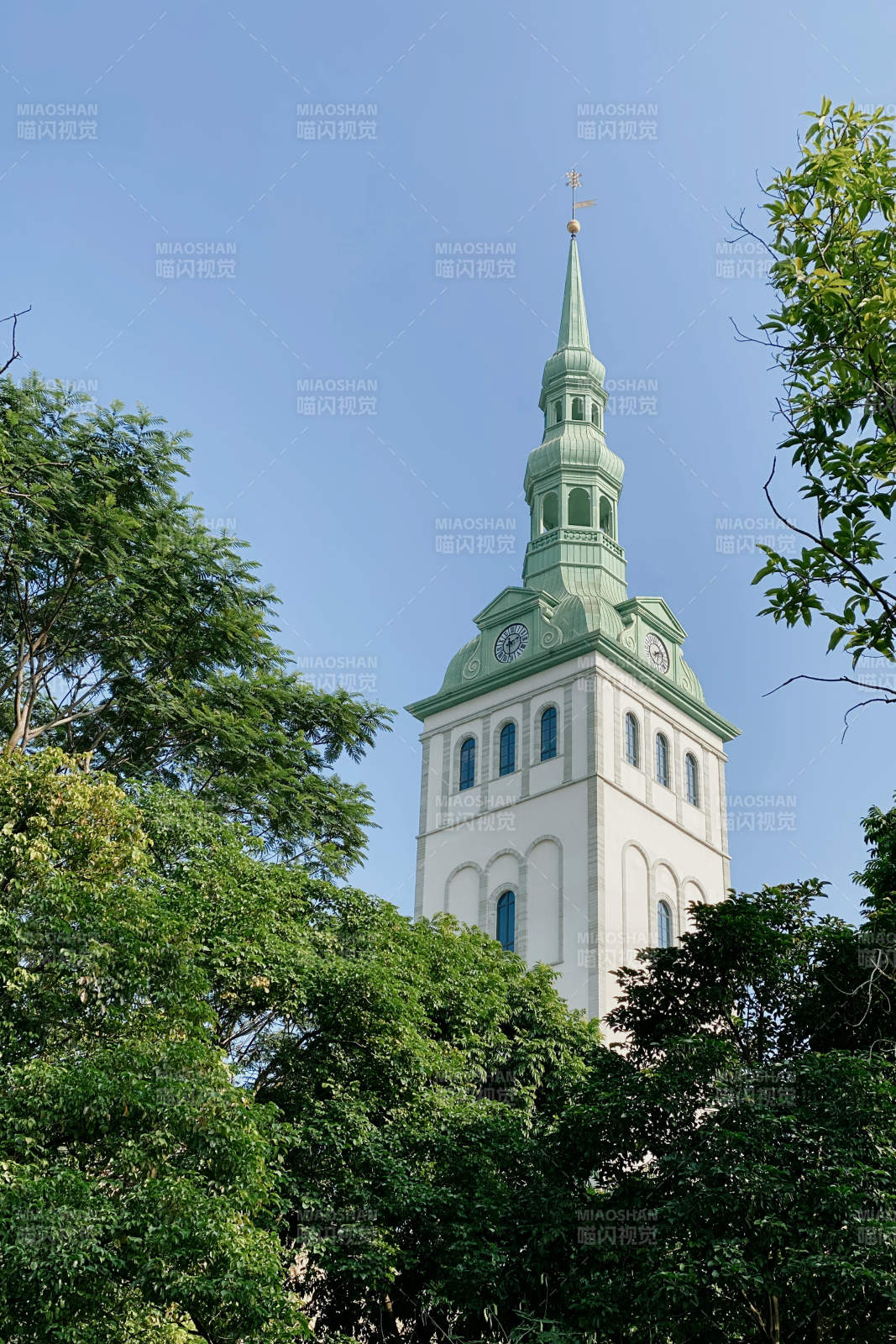 绿树环绕的尖顶教堂塔楼图片