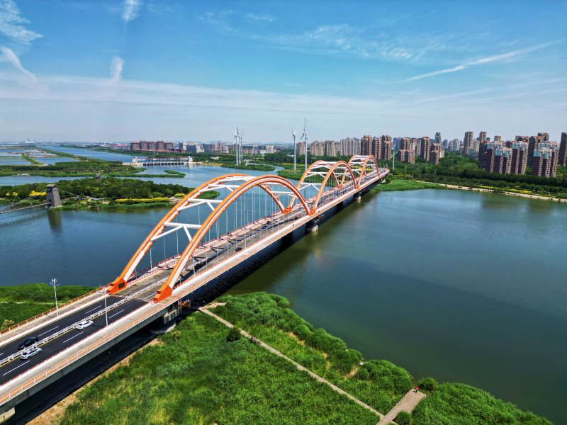 现代拱桥横跨碧水绿岸图片