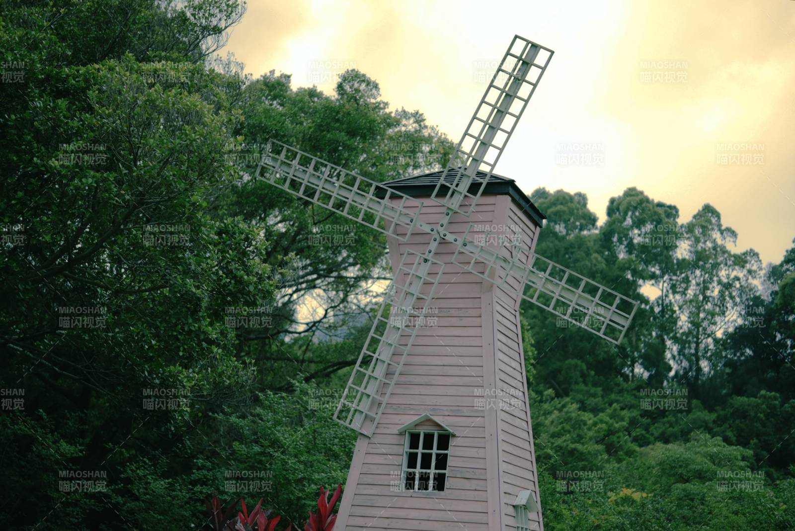 粉色风车与绿树相映成趣图片