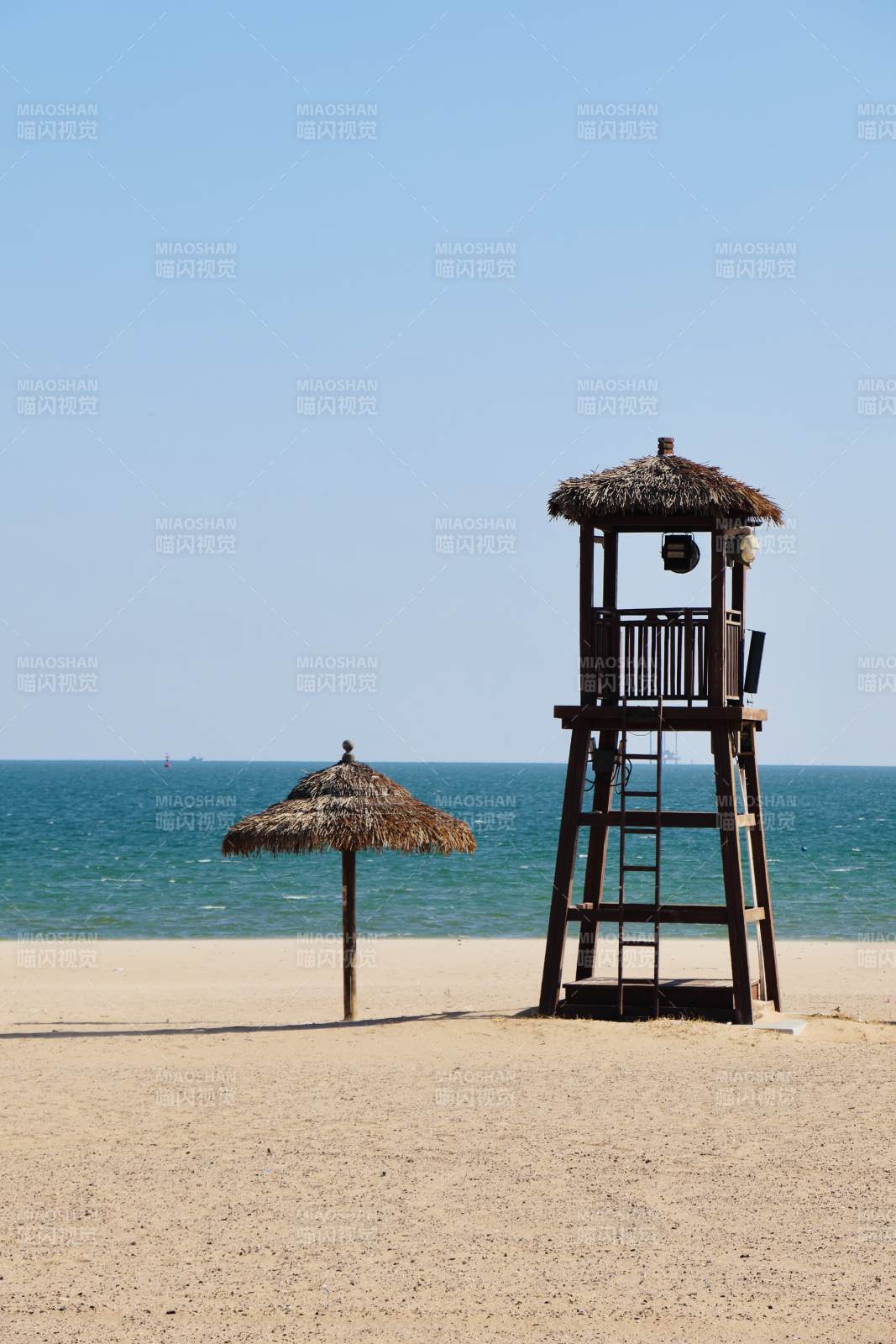 海滩上的瞭望塔和草伞图片