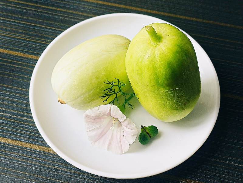 青色果实与花瓣装饰盘中图片