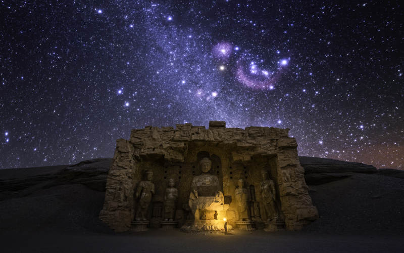 星空下的古老石窟雕像图片
