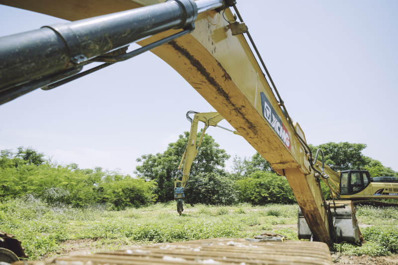 挖掘机在绿色田野中作业图片