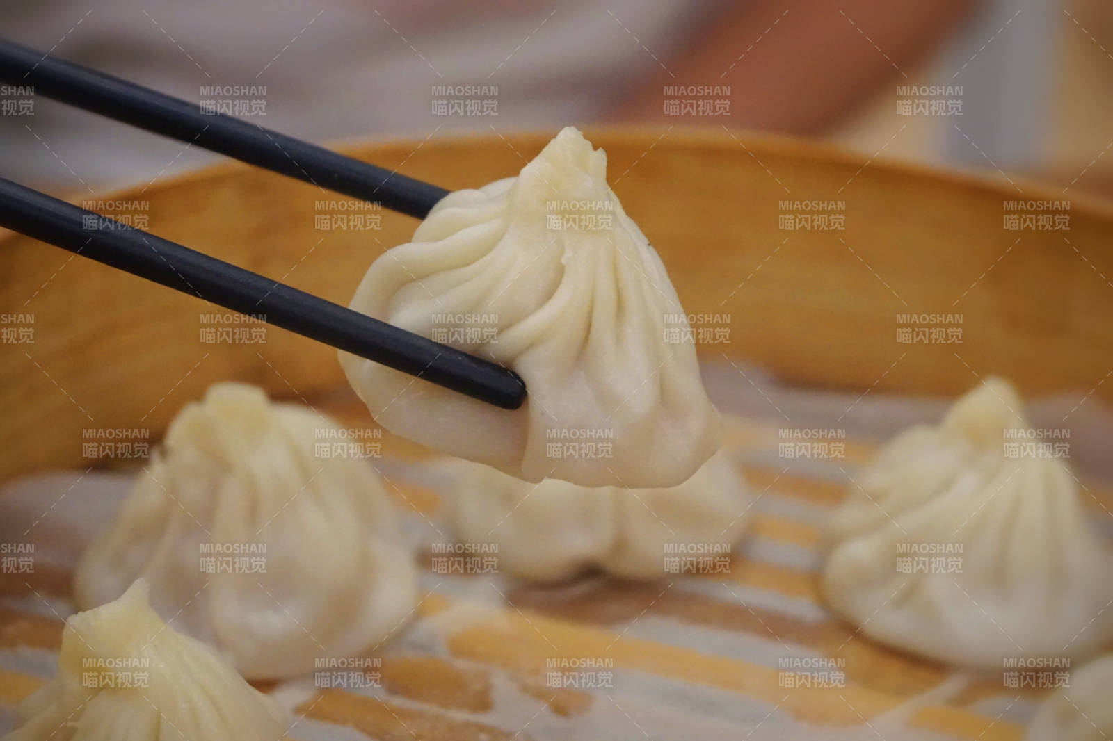 筷子夹起的小笼包特写图片