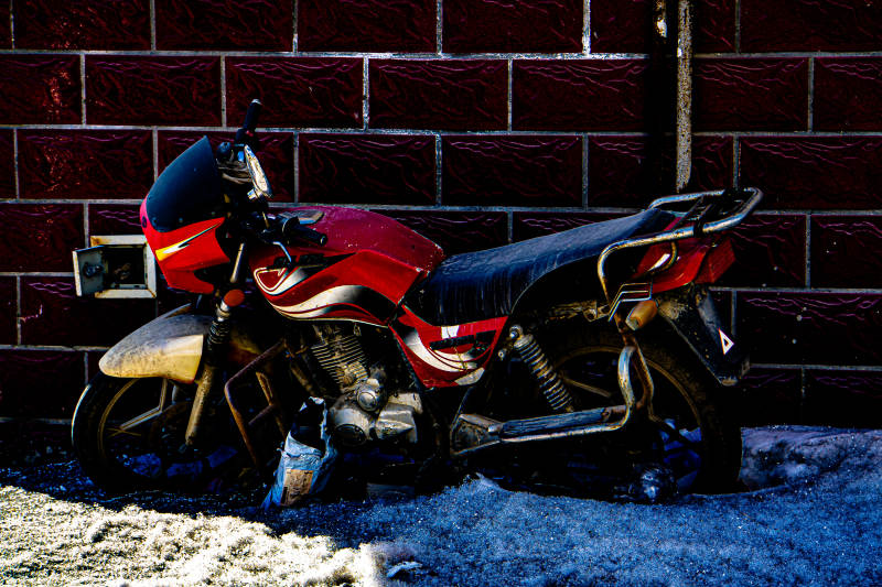 红色摩托车停靠在墙边图片
