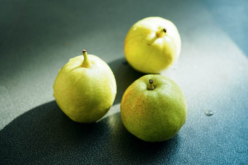 三颗青梨静置于桌面图片