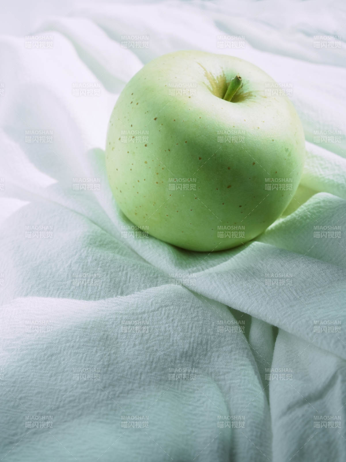 青苹果静卧柔软布料上图片