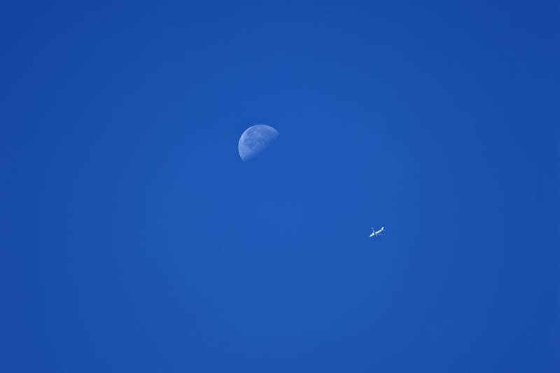 蓝天下的月亮与飞机图片