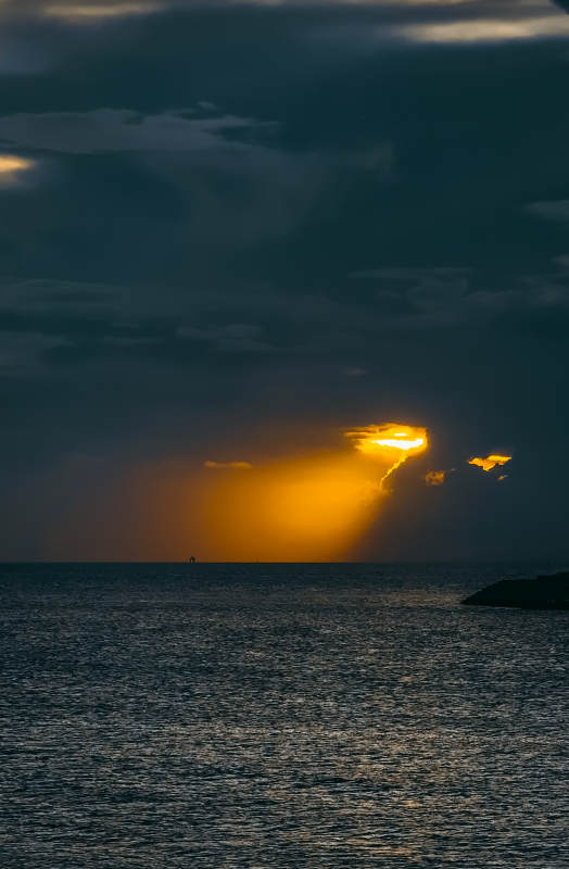 夕阳穿透云层照耀海面图片