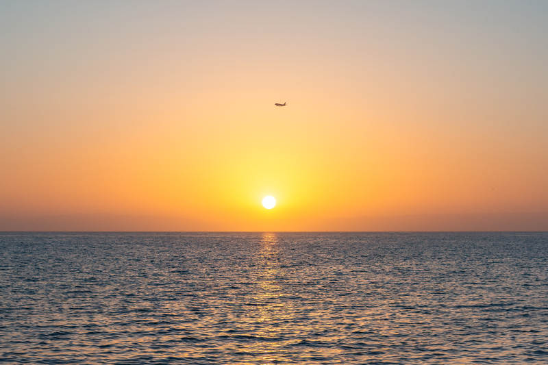 夕阳海面飞机掠影图片