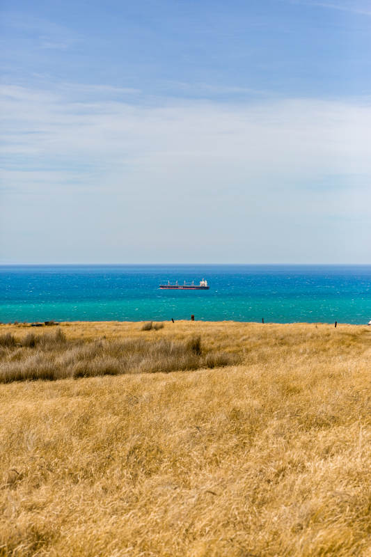 海边草地与远航货船图片