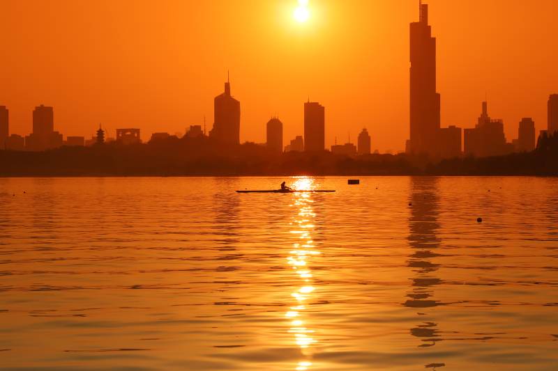 夕阳下的城市与划船者图片