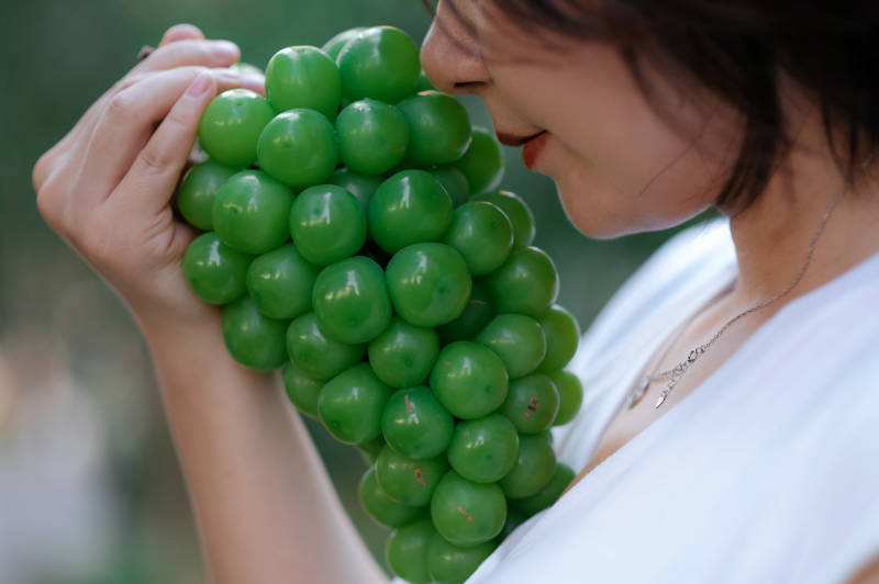 女子轻嗅绿色葡萄图片